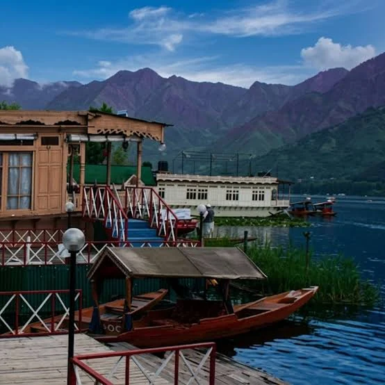 A shikara on a still Kashmiri lake below snow mountains